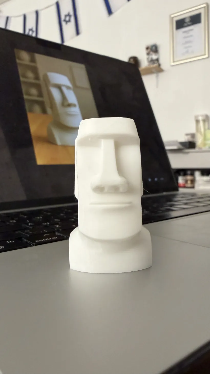 A white 3D printed moai statue standing on a desk